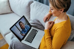 woman using laptop having video call with her doctor while sitting home 